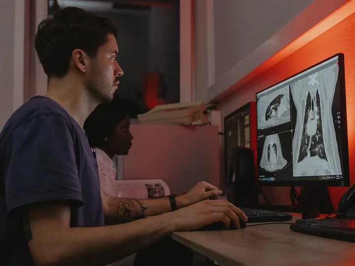 Two scientists sitting at computer looking at radiology images.