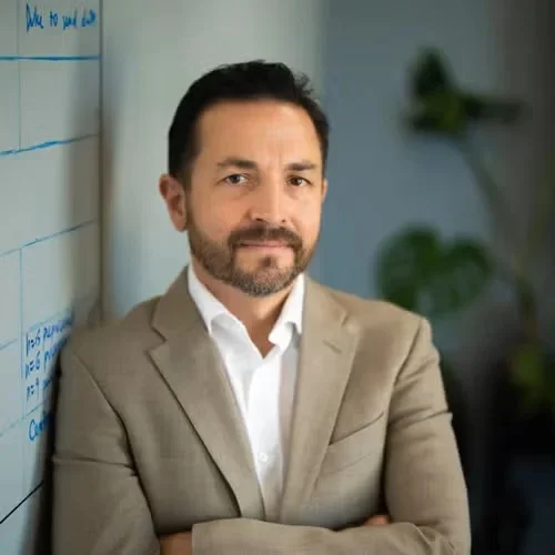 ben ellingson wearing a tan suit leaning against his office wall board