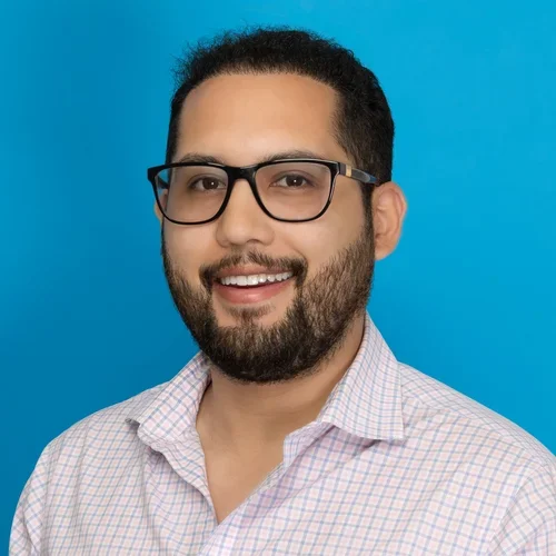 daniel gomez wearing a white checkered button up shirt on a bright blue background