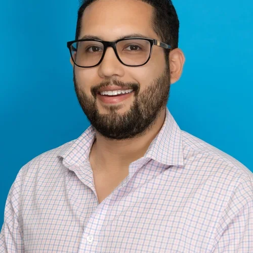 daniel gomez wearing a white checkered button up shirt on a bright blue background