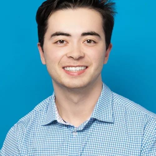tristan kelly wearing a light blue button up shirt on a bright blue background