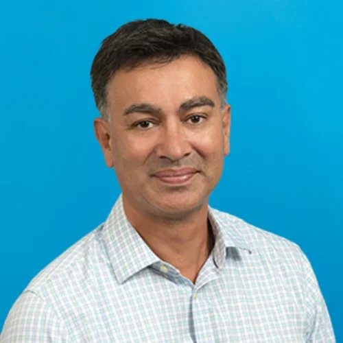 matthew brown wearing a checkered button up shirt on a bright light blue background