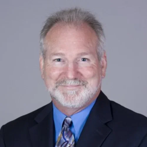 michael mcnitt-gray wearing a black suit and tie on a gray background