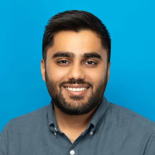 dhruvin shah wearing a charcoal button up shirt on a bright blue background