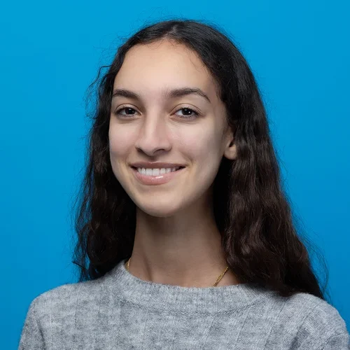 marie tafese wearing a gray sweater on a bright blue background
