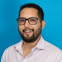 daniel gomez wearing a white checkered button up shirt on a bright blue background