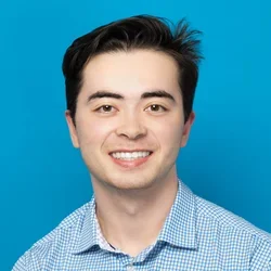 tristan kelly wearing a light blue button up shirt on a bright blue background