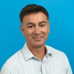 matthew brown wearing a checkered button up shirt on a bright light blue background