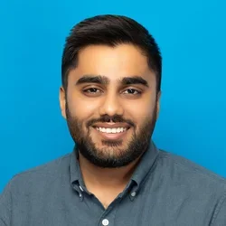 dhruvin shah wearing a charcoal button up shirt on a bright blue background