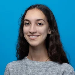 marie tafese wearing a gray sweater on a bright blue background