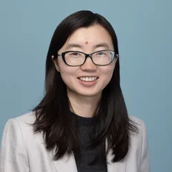 jingwen yao in a light gray suit jacket on a light bluish gray background